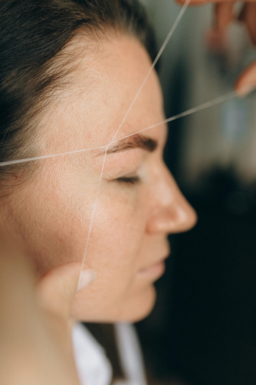 Eyebrow threading — cotton thread shaping brow in profile